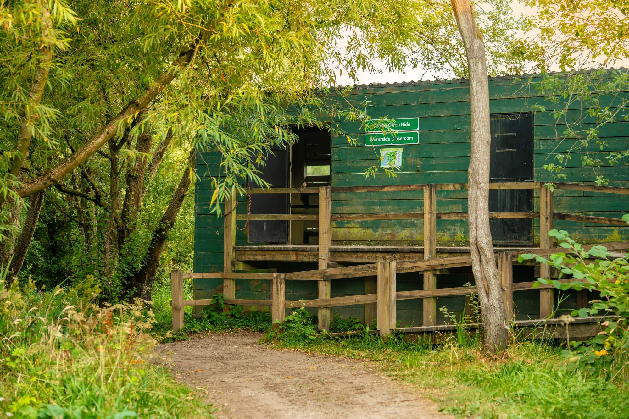 The Charlie Owen Hide and Waterside Classroom at Pennington Flash Country Park, Leigh — a green timber hide with viewing shutters over the water